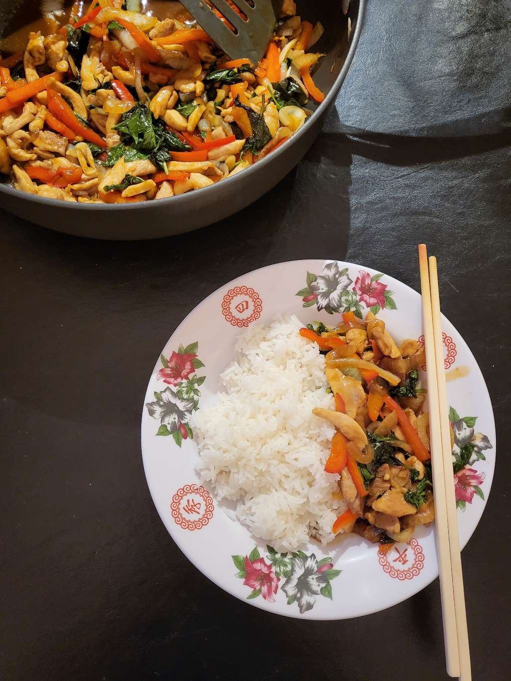 Bowl of rice and stir fry with chopsticks and more stir fry on the side