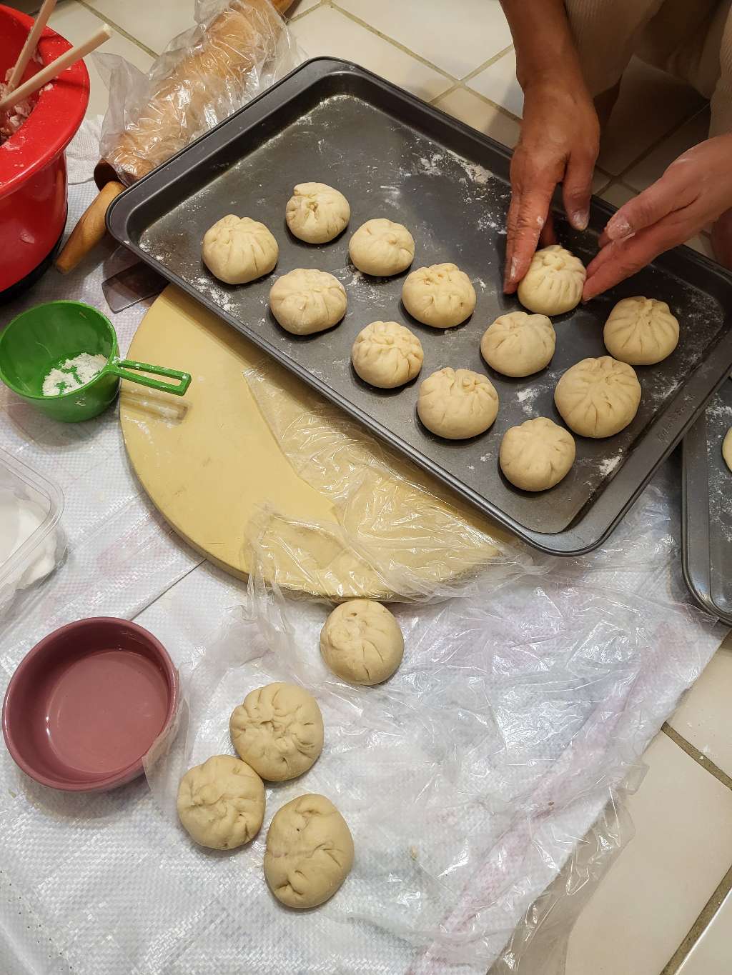 Laying out pieces of uncooked bao on a baking tray