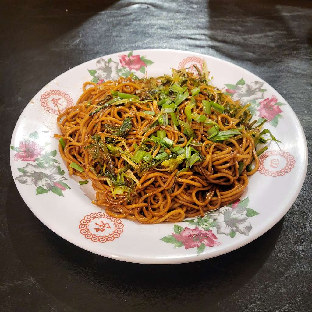 A plate of stir fried noodles with scallions on top