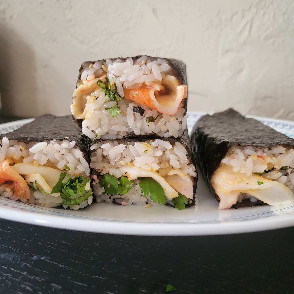 Three imitation crab musubis lying next to each other, and another one sitting on top