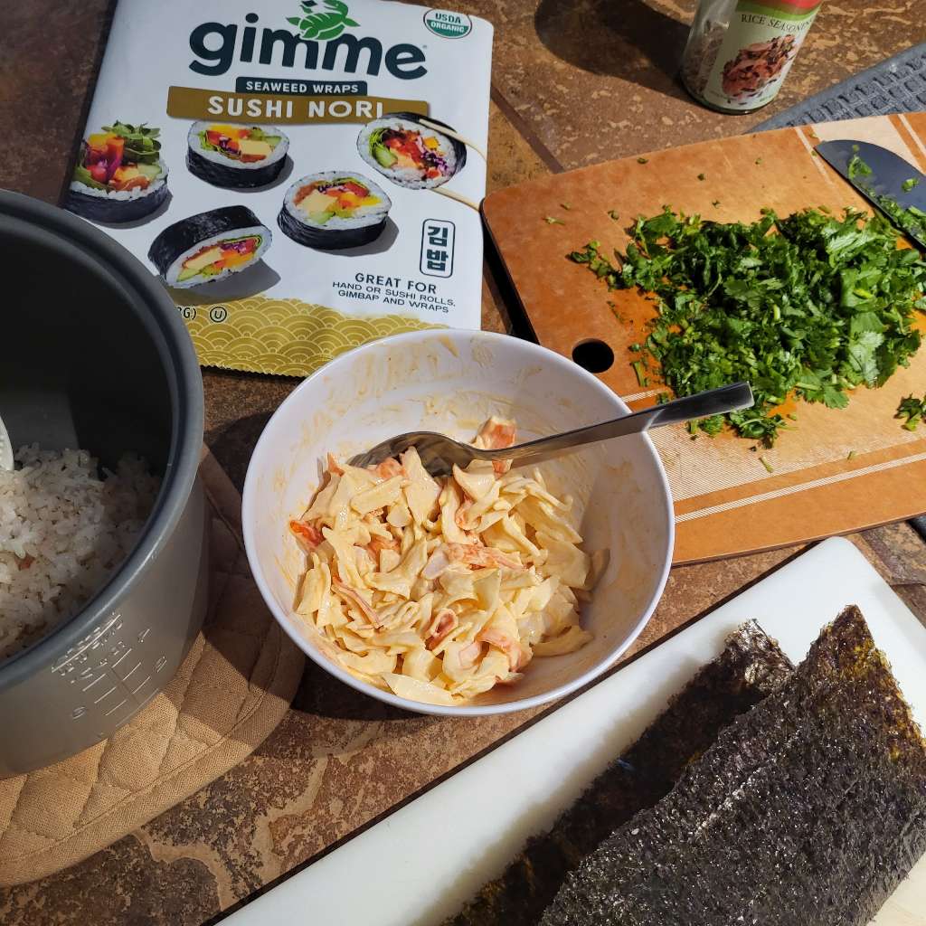 Some shredded imitation crab mixed with mayo and sriracha, along with some nori, some cut up cilantro, and rice mixed with furikake
