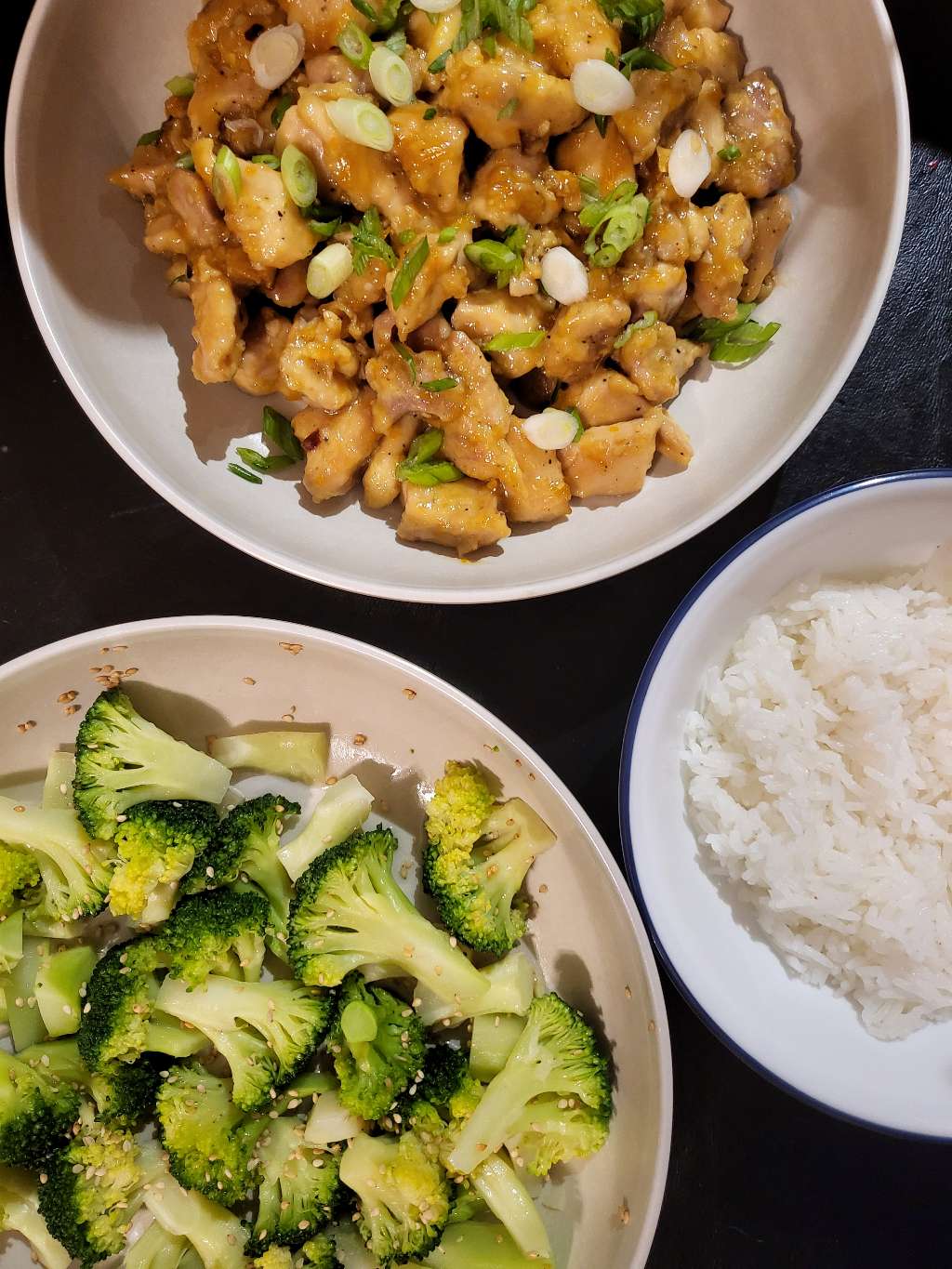 Overhead view of the orange chicken, as well as a plate of broccoli, and a plate of rice