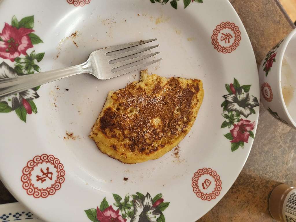 A small piece of a pancake with some cinnamon sugar sprinkled on top