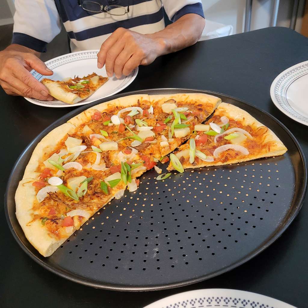 Some slices of some  BBQ chicken pizza that I made, and my dad is eating it in the background