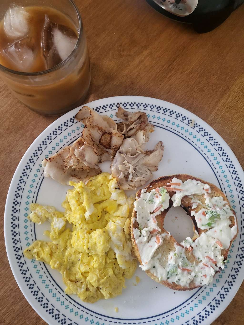 Some cooked turkey slices, scrambled eggs, and half a bagel with veggie cream cheese