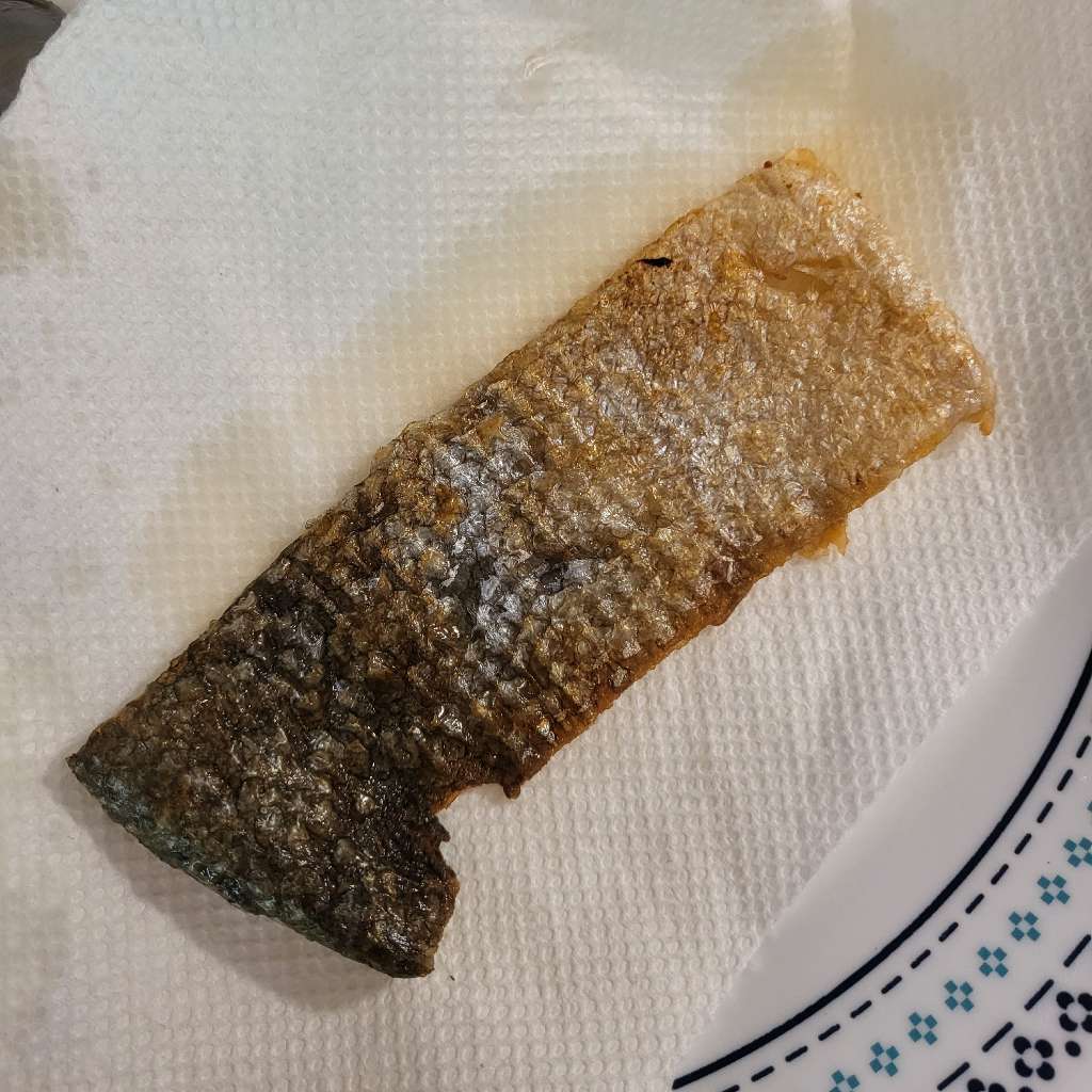 A piece of fried salmon skin on a paper towel