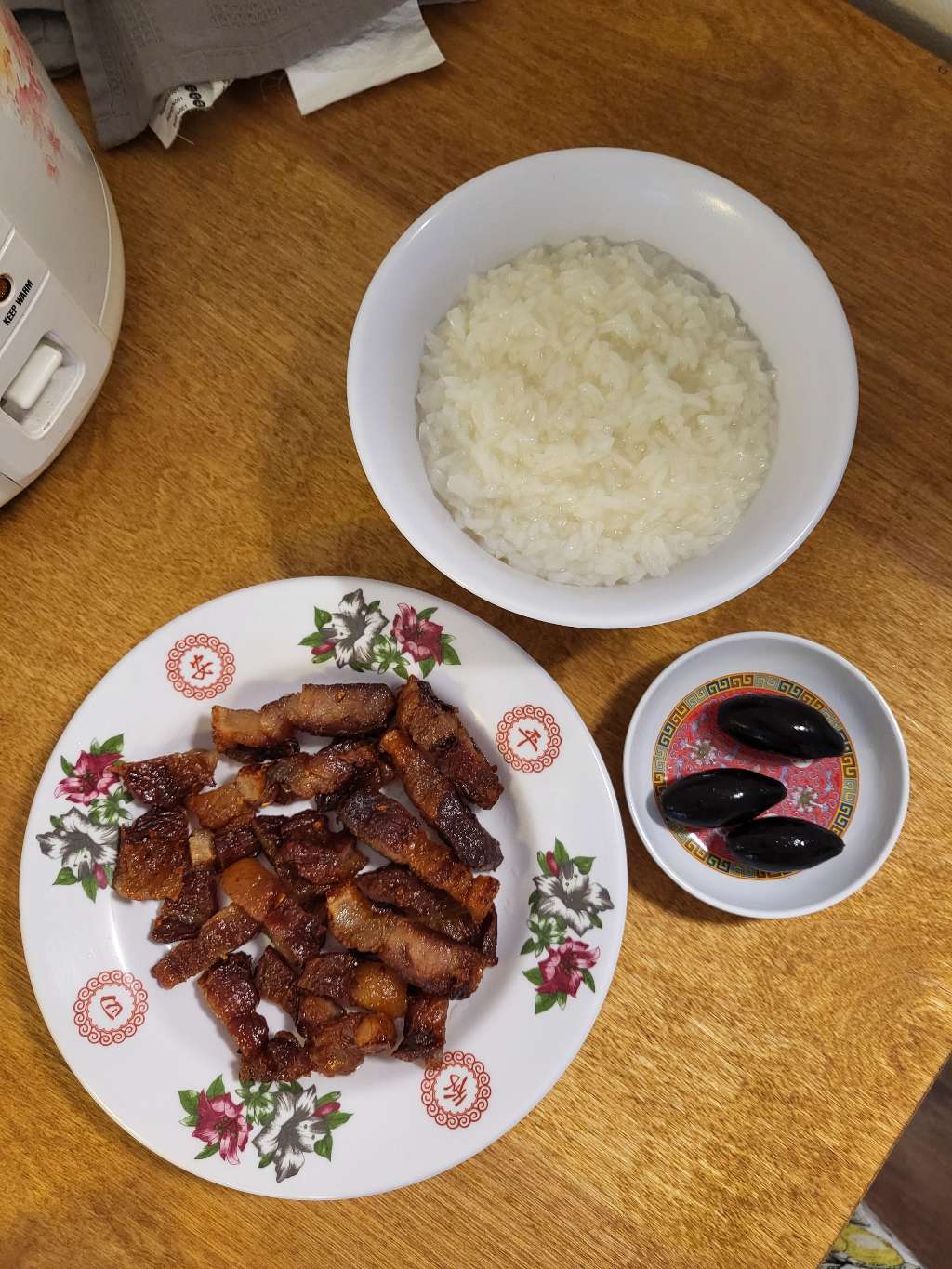 An overhead shot of porridge, black olives, and cured meat