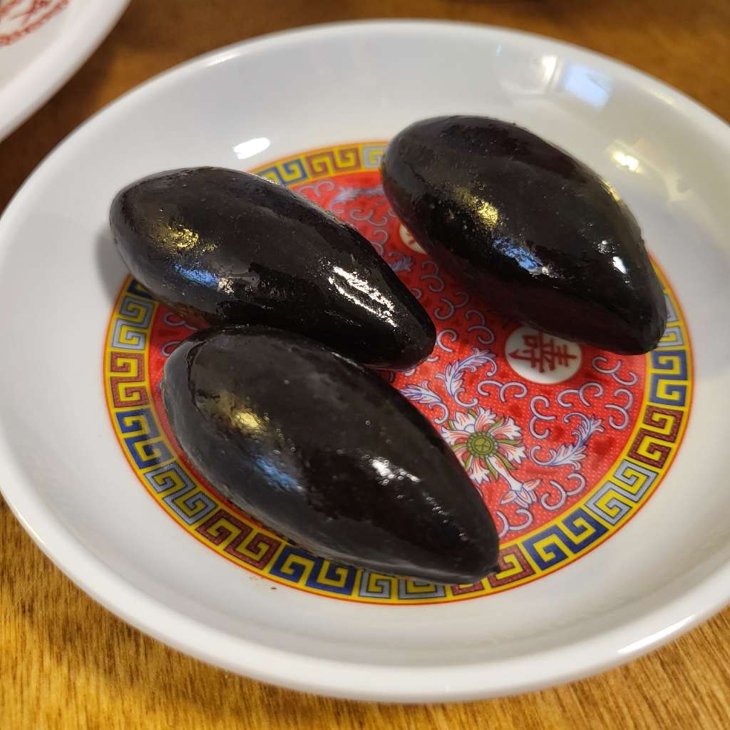 Three black olives in a saucer